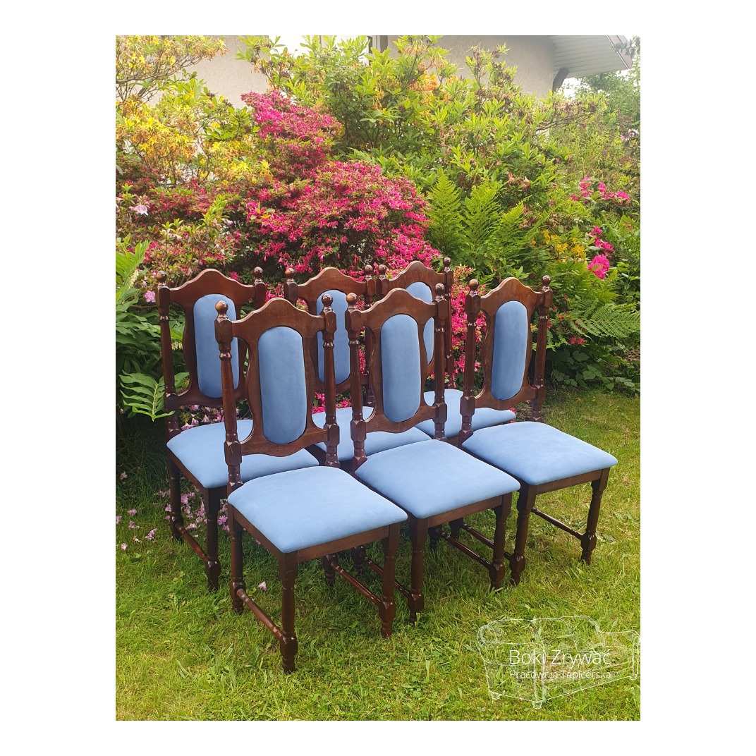 Sześć odnowionych krzeseł z ciemnego drewna z jasnoniebieską tapicerką, ustawionych na trawie na tle kwitnących krzewów w ogrodzie. Widoczny delikatny logotyp w prawym dolnym rogu.