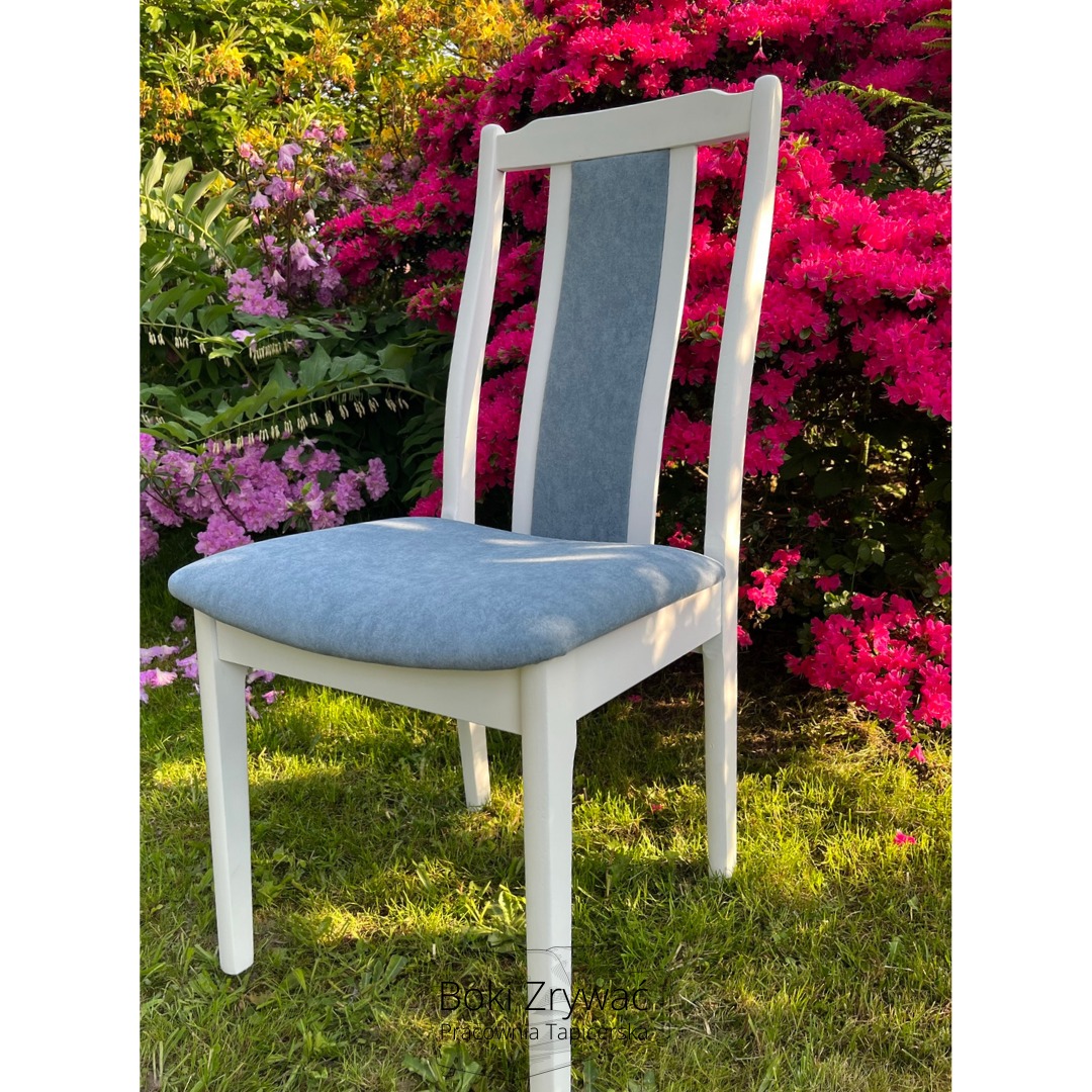 Odnowione krzesło z jasną tapicerką siedziska i oparcia na tle kwitnących krzewów w odcieniach różu i fioletu, stojące na trawie.