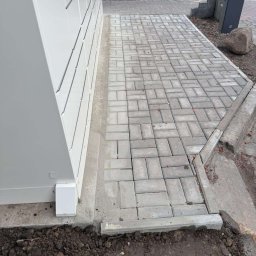 Oscar Kamil Osinski - Ułożona kostka brukowa przy paczkomacie, widoczne świeże ślady po cięciu kostki i ziemia.