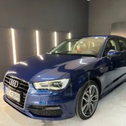 Błyszczący, granatowy Audi A3 po detailingu. Widoczne odbicie światła na lakierze, felgi aluminiowe. Tablica rejestracyjna widoczna.