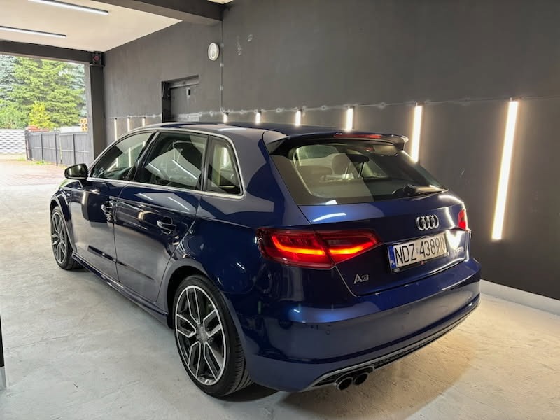 Granatowy Audi A3 po detailingu, widoczne tylne światła, tablica rejestracyjna NDZ 43890, sportowe felgi. Auto w studiu detailingowym, oświetlenie LED.