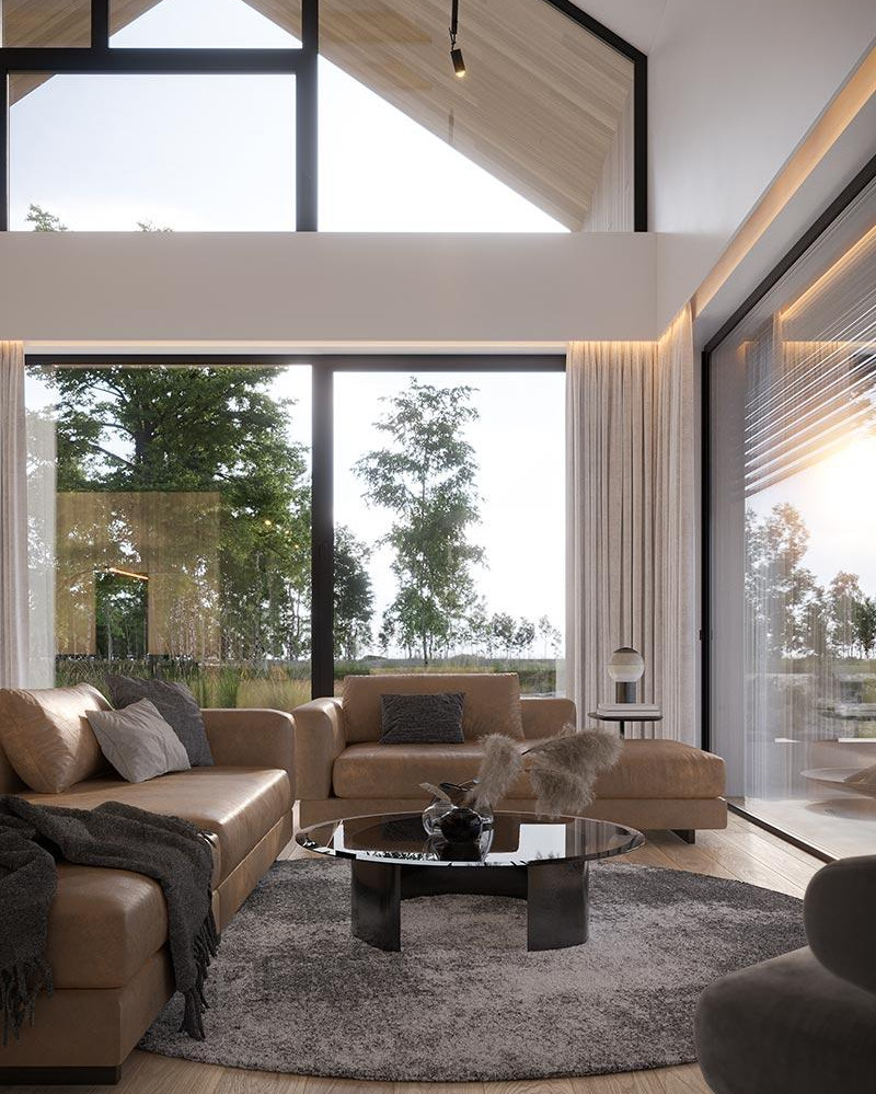 Jasny salon z dużymi oknami wychodzącymi na zieleń, skórzane sofy i okrągły stolik kawowy na puszystym dywanie, drewniany sufit z czarnymi belkami.