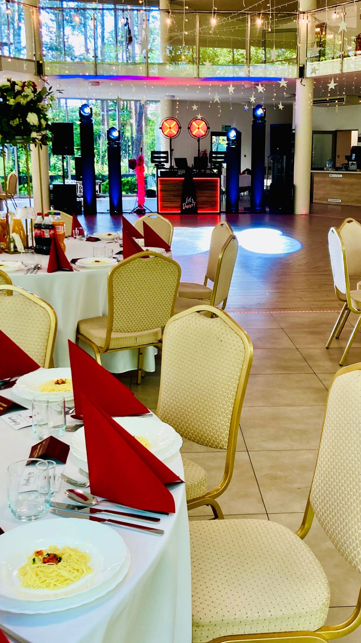 Uroczysta sala bankietowa z oświetleniem scenicznym i dekoracjami gwiazdkowymi, przygotowana do imprezy z nakrytymi stołami i krzesłami.