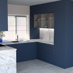 HAD Project - Wizualizacja nowoczesnej kuchni z zabudową w odcieniach granatu, marmurowym blatem i podświetlaną przestrzenią nad nim, minimalistyczne uchwyty w kolorze miedzi, zlew przy oknie z żaluzjami.