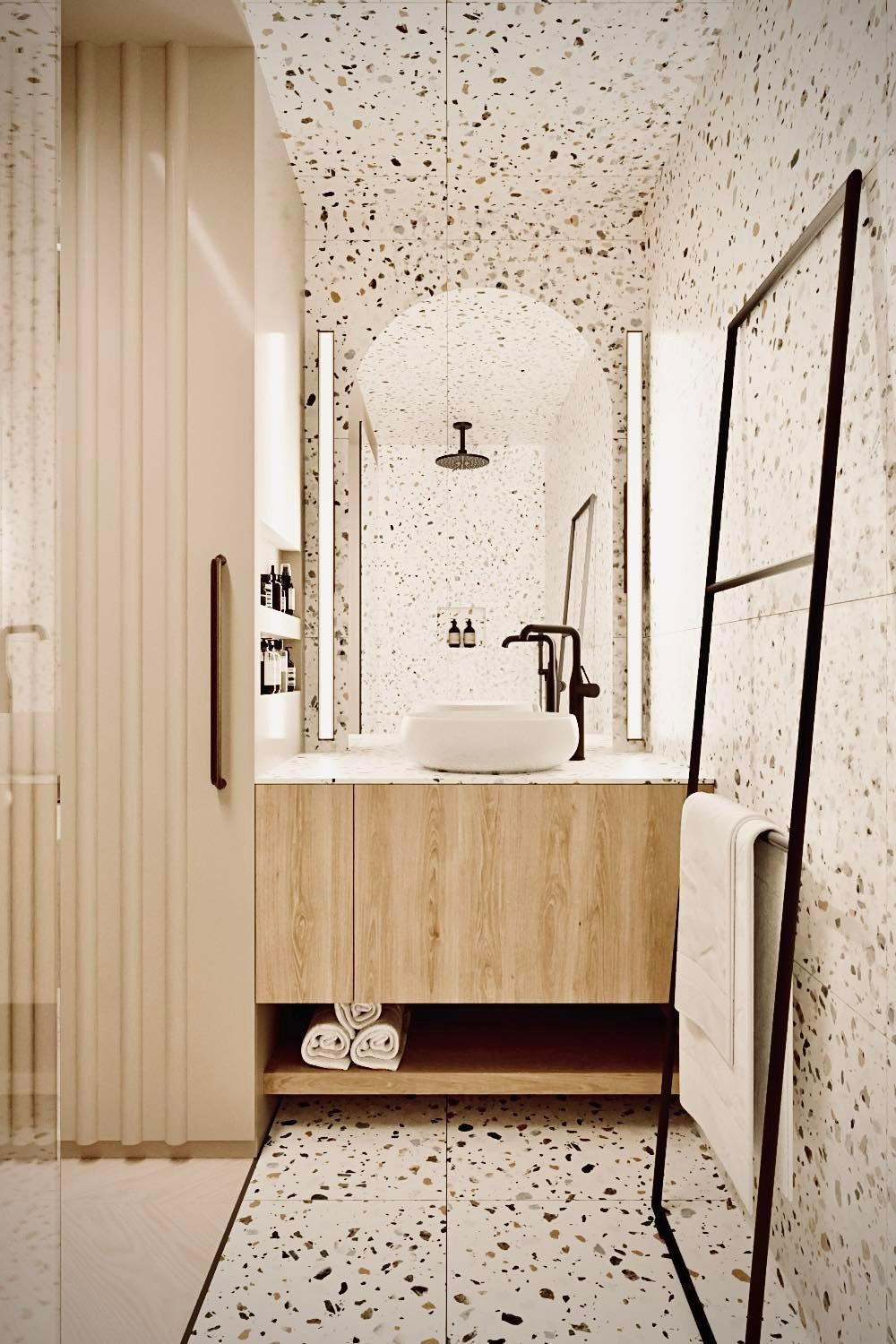 Nowoczesna łazienka z umywalką nablatową, drewnianą szafką pod umywalką, lustrem w kształcie łuku z podświetleniem LED oraz ścianami i podłogą wykończonymi płytkami imitującymi lastryko.