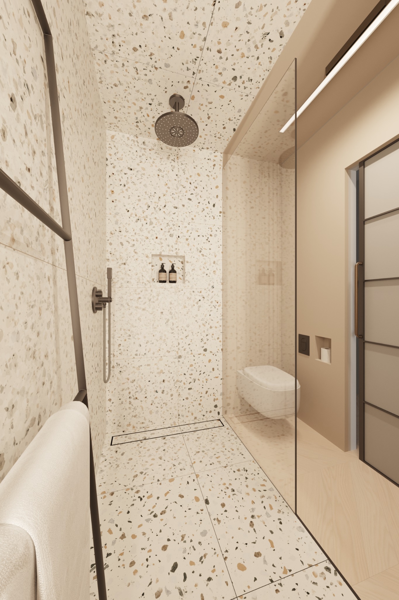 Nowoczesna łazienka z prysznicem typu walk-in, wykończona płytkami terazzo w odcieniach beżu i bieli, z minimalistyczną armaturą w kolorze grafitowym, wbudowanymi półkami na kosmetyki i ręcznikiem...