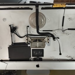 Fix Lab Center sp. z o.o. - Wnętrze rozłożonego komputera iMac z widocznymi elementami elektroniki, kablami i radiatorem, ukazujące etap naprawy lub serwisu sprzętu komputerowego.