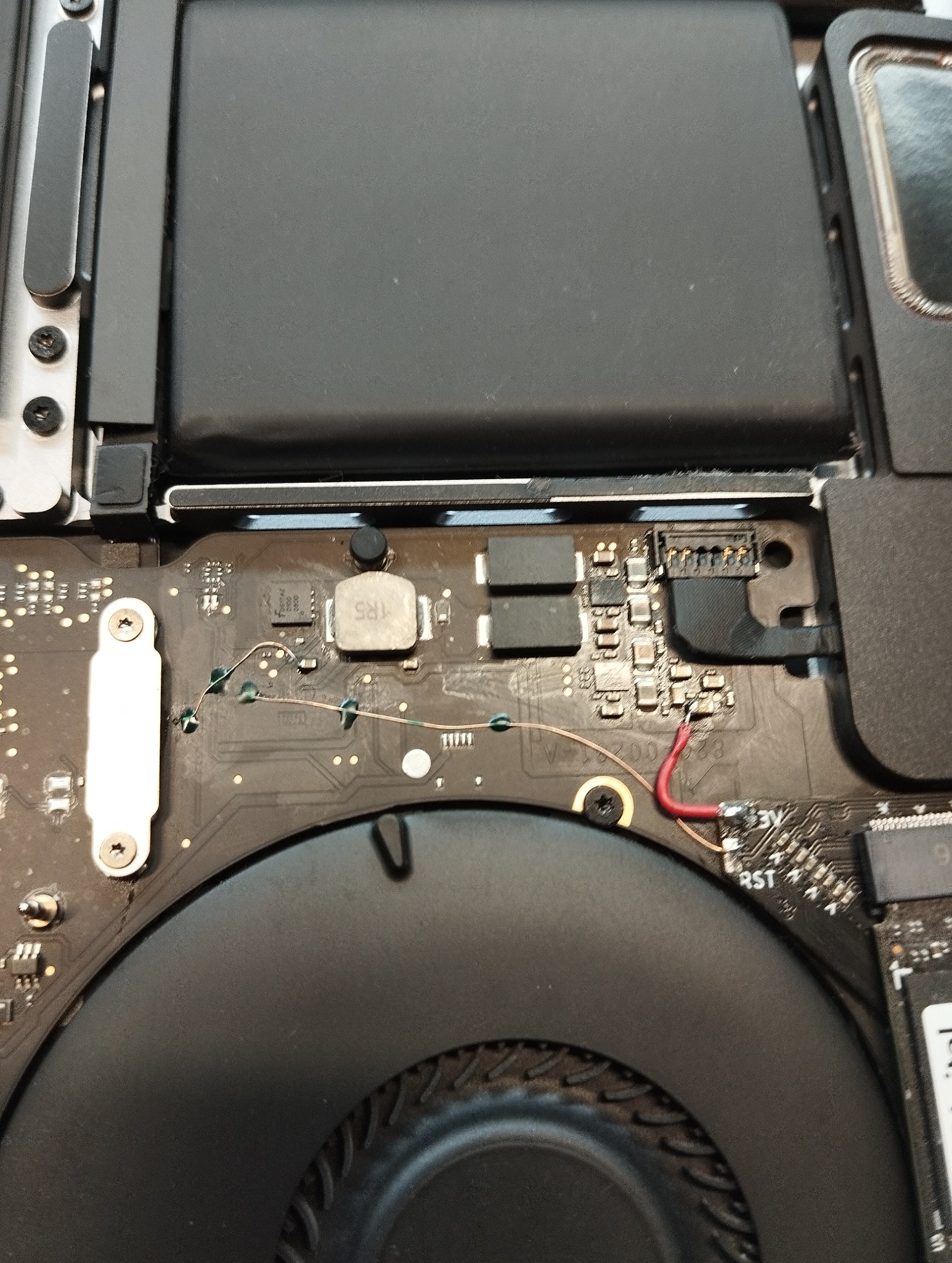 Wnętrze laptopa po naprawie: płyta główna z elementami elektronicznymi, wentylator, przewody. Widoczne ślady lutowania, co sugeruje serwis elektroniki.