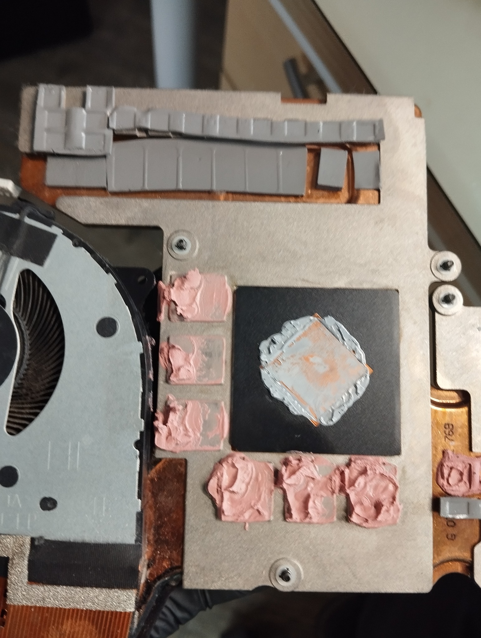 Otwarty laptop z widocznym układem chłodzenia, pastą termoprzewodzącą i elementami radiatora. Detal naprawy komputera, bliskie ujęcie, widoczne ślady użycia.