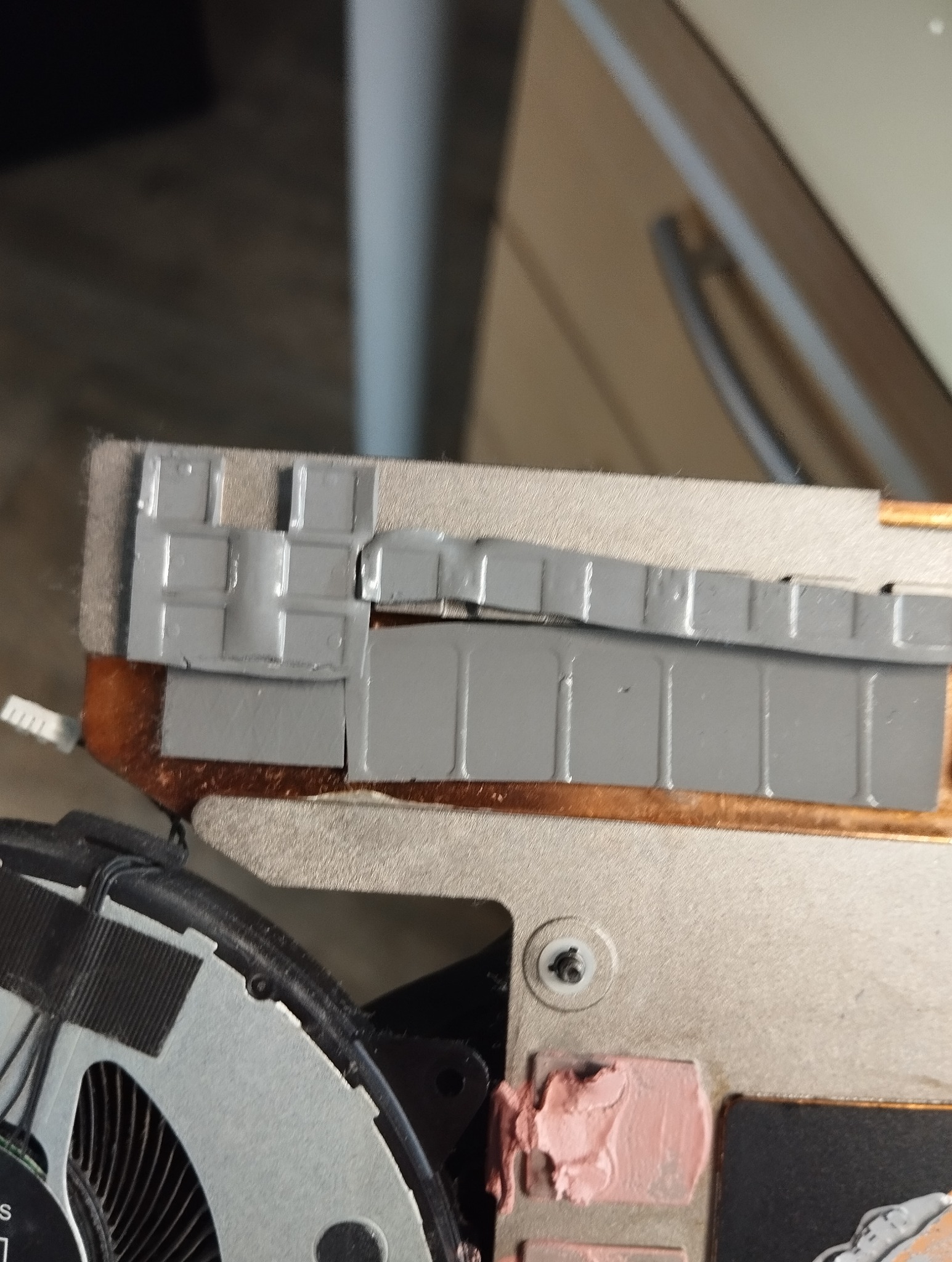 Wnętrze laptopa: radiator z termopadami i wentylator po czyszczeniu, widoczna pasta termoprzewodząca. Bliski kadr, detale naprawy laptopa, elementy chłodzenia.