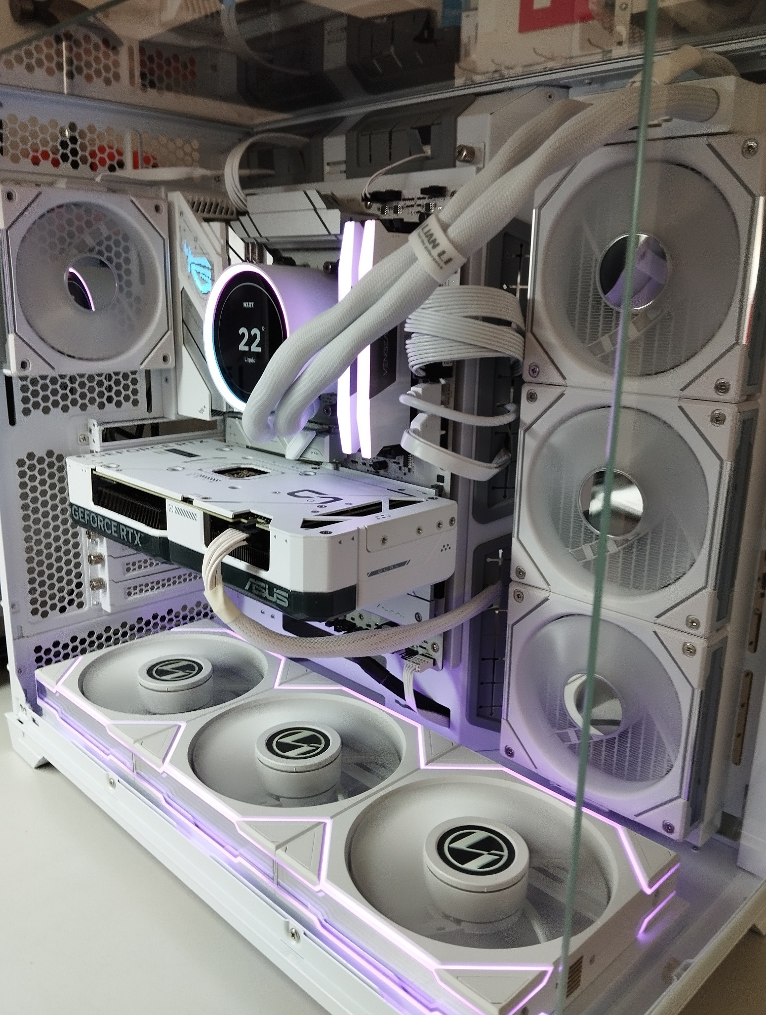 Biała obudowa komputera PC z podświetleniem LED, widoczne wentylatory Lian Li, karta graficzna GeForce RTX i chłodzenie wodne NZXT, wnętrze komputera.