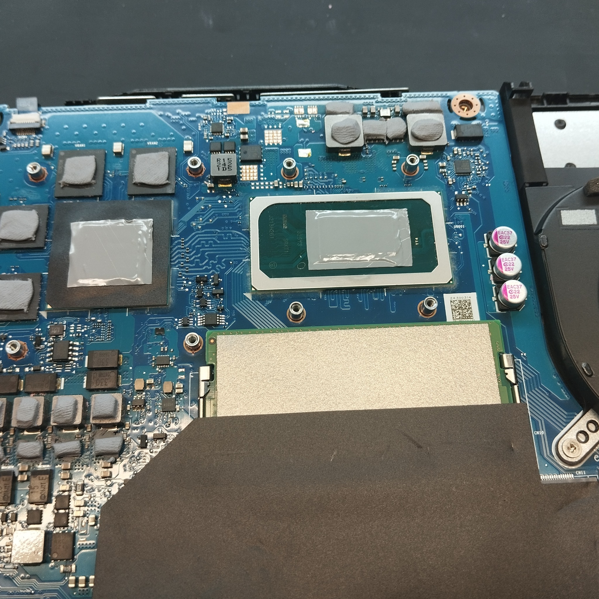 Płyta główna laptopa po wymianie pasty termoprzewodzącej na procesorze i układach chłodzenia. Widoczne radiatory i elementy elektroniczne.