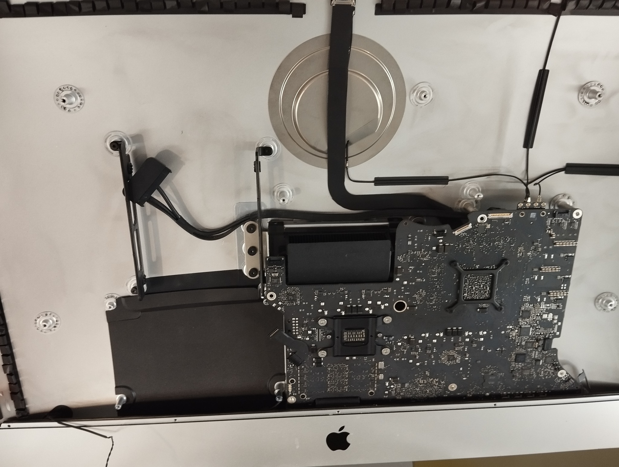 Wnętrze naprawianego komputera iMac, widoczna płyta główna, radiator i inne komponenty. Sprzęt po demontażu, w trakcie serwisu.