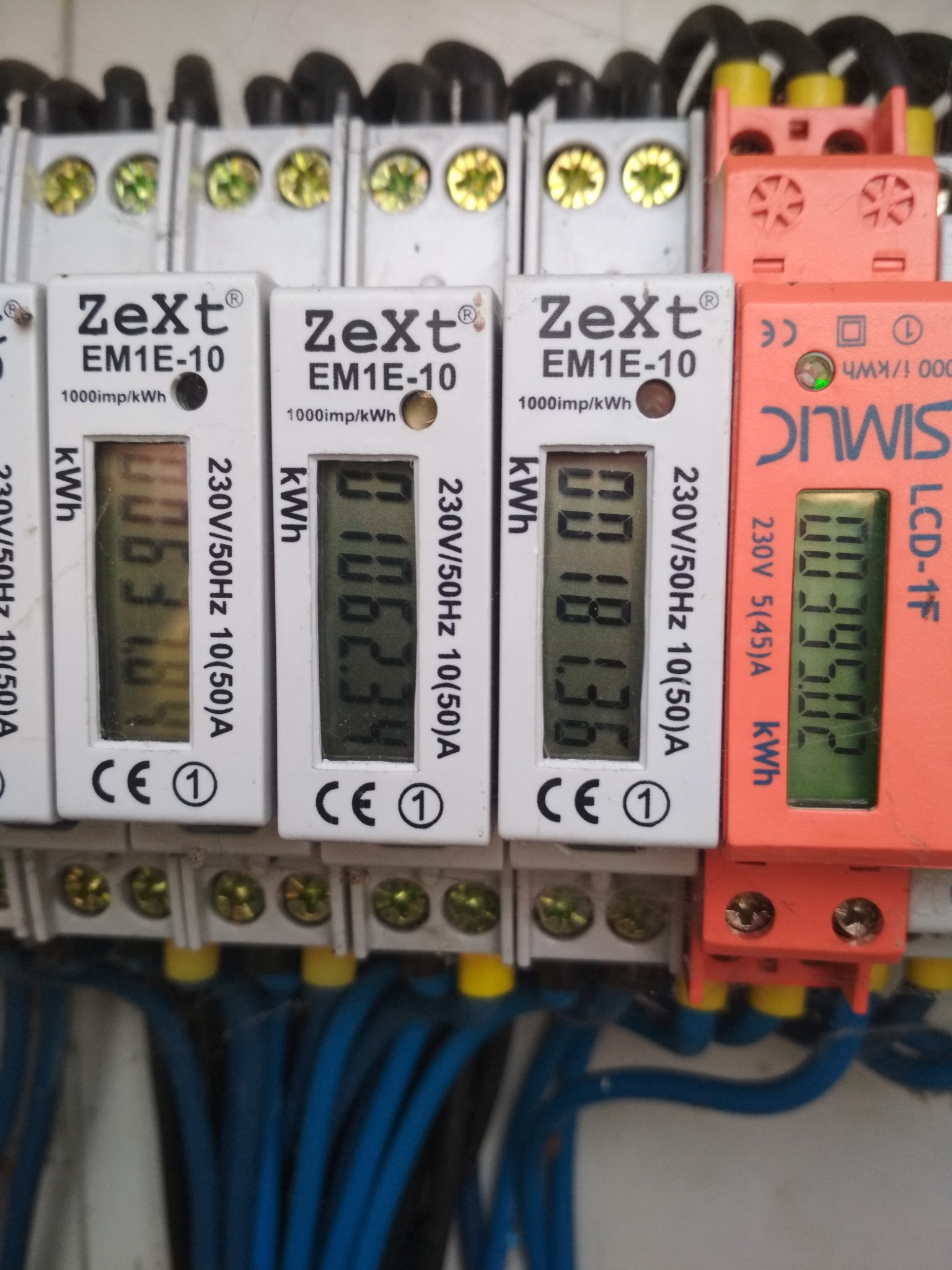 Szczegółowe ujęcie liczników energii elektrycznej Zext i Simlic w rozdzielnicy, widoczne wartości zużycia energii.