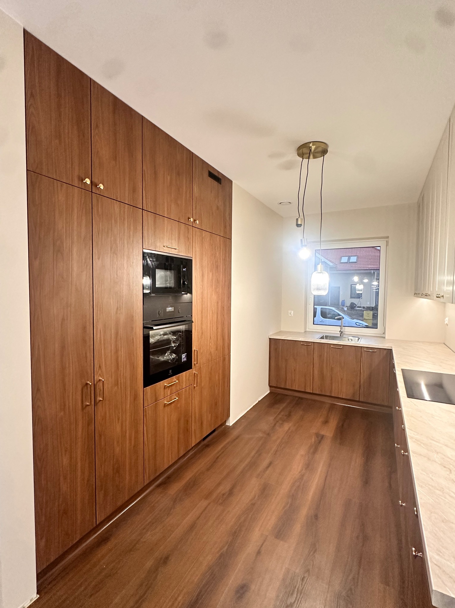 Nowoczesna kuchnia w Małkini z zabudową drewnianą pod sufit, z wbudowanym piekarnikiem i mikrofalówką, oraz drewnianymi blatami i podłogą.