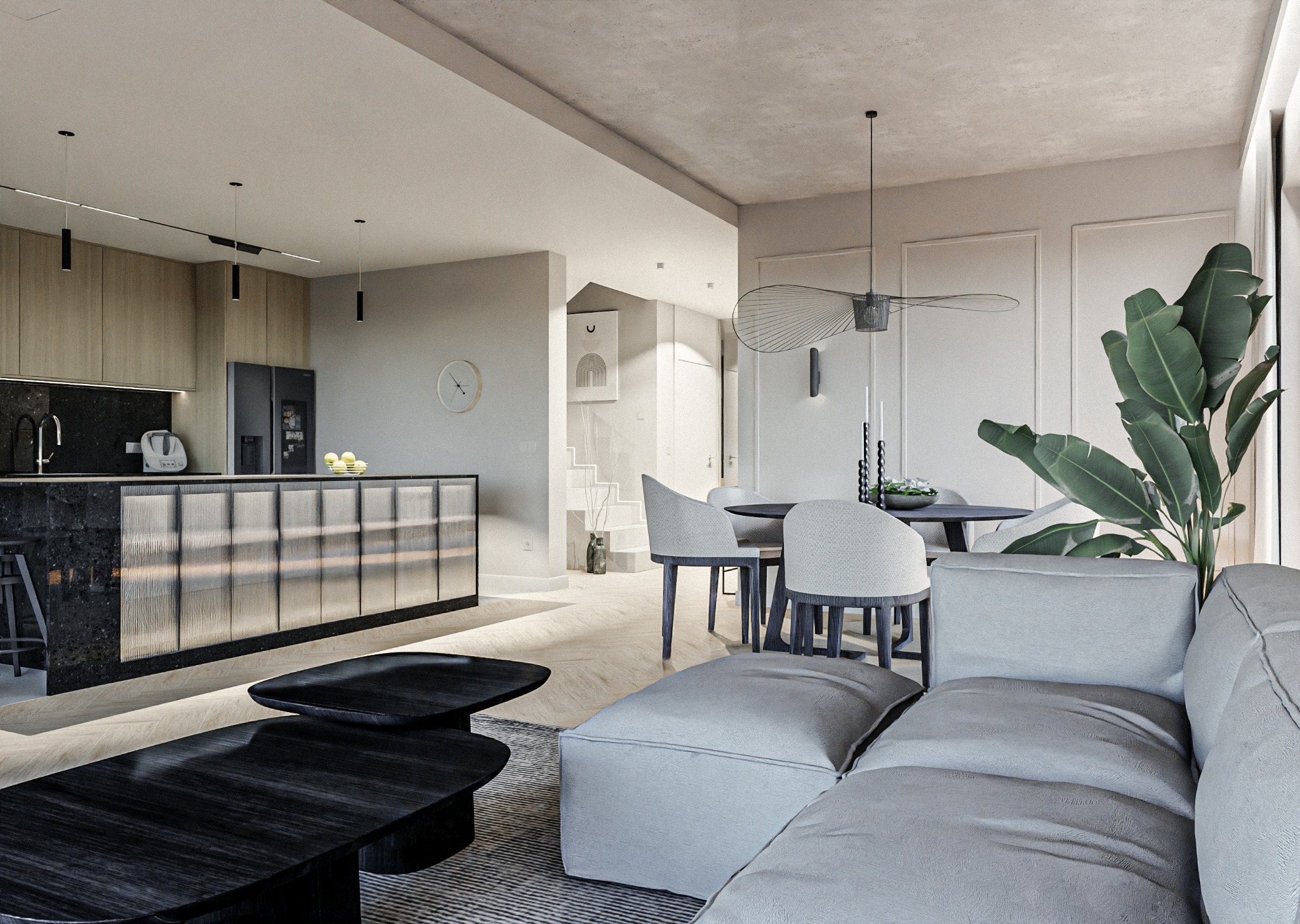 Jasne, przestronne wnętrze z otwartą kuchnią, jadalnią i salonem; czarny, marmurowy blat kuchenny z barkiem; okrągły stół z szarymi krzesłami; szara sofa z poduszkami; czarne, drewniane stoliki kawowe