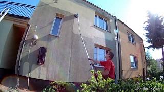 Czyszczenie elewacji domu jednorodzinnego z użyciem lancy teleskopowej, widoczna drabina oparta o ścianę budynku.