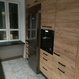 Oskarro - Nowoczesna kuchnia z drewnianymi szafkami, zabudowanym piekarnikiem Electrolux, lodówką side-by-side i wzorzystą podłogą z płytek ceramicznych.