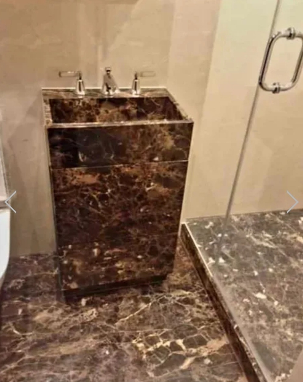 Marmurowa umywalka nablatowa z szafką w łazience, dopasowana kolorystycznie do podłogi i blatu prysznica, z chromowaną armaturą.