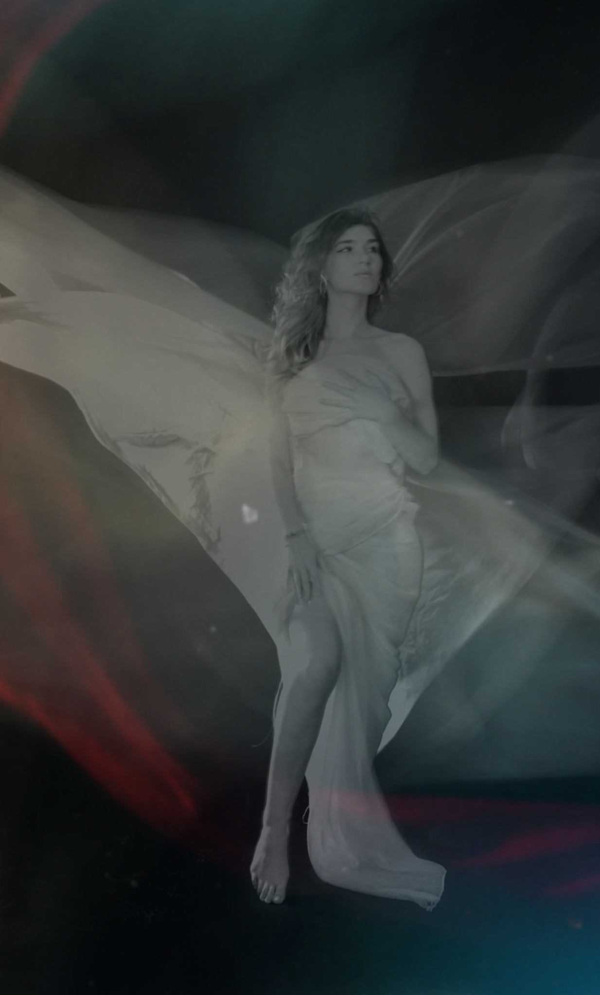 Portret kobiety owiniętej w zwiewną tkaninę na ciemnym tle z delikatnymi efektami świetlnymi, stylizowane ujęcie.