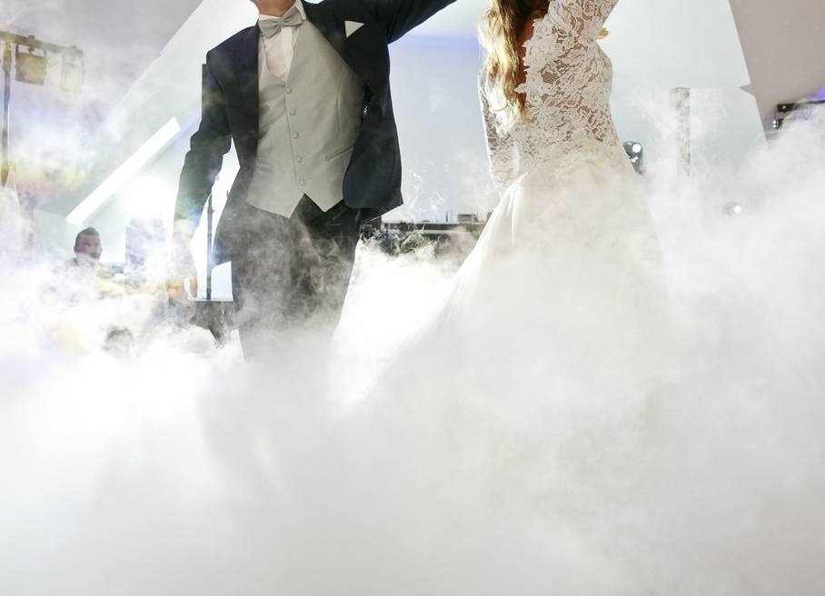 Para młoda w tańcu, otoczona efektem ciężkiego dymu, oświetlenie sceniczne w tle.