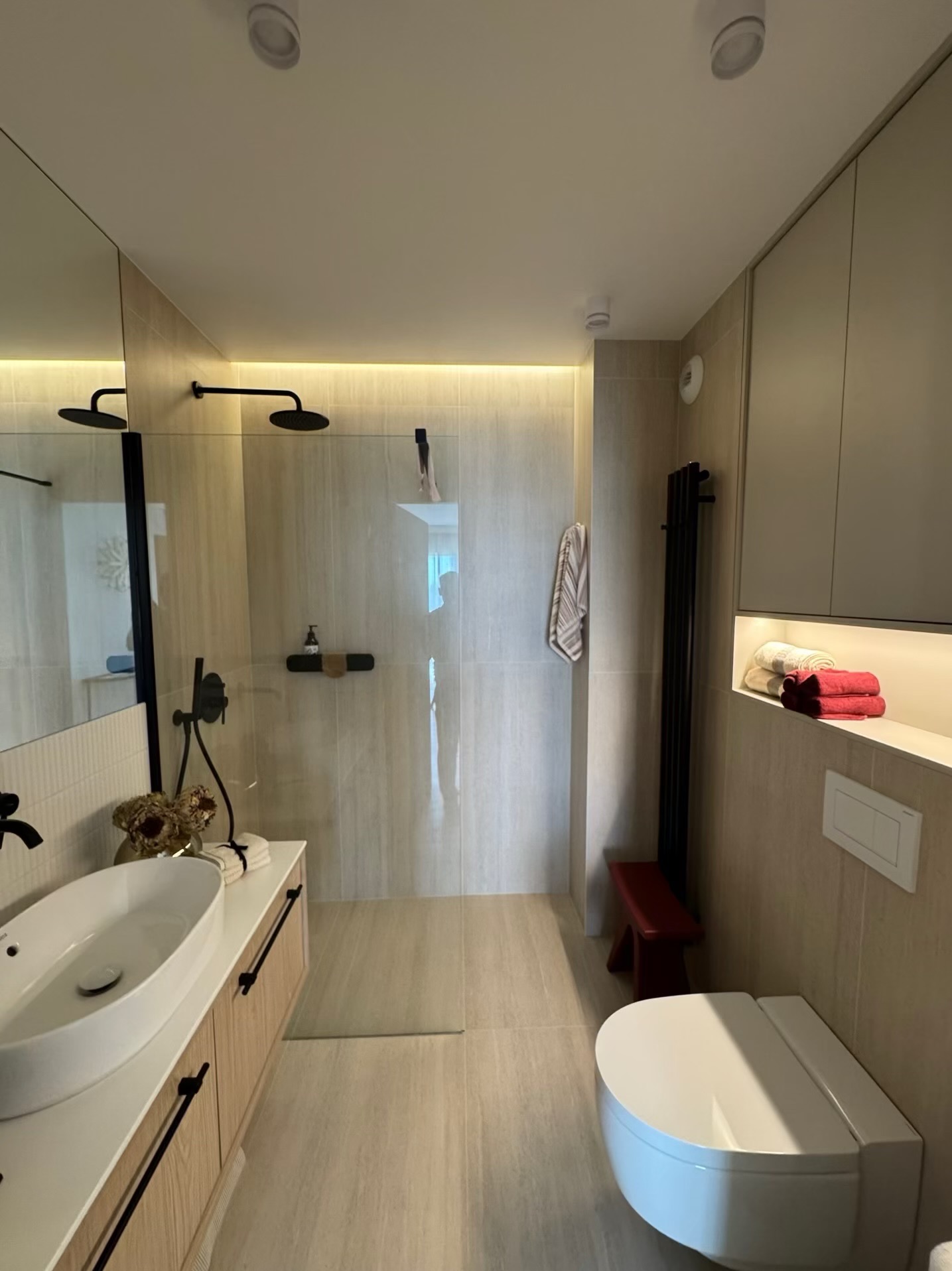 Nowoczesna aranżacja jasnej łazienki z kabiną typu walk-in, umywalką nablatową i czarnymi akcentami, zrealizowana w Gdańsku. Minimalistyczny design.