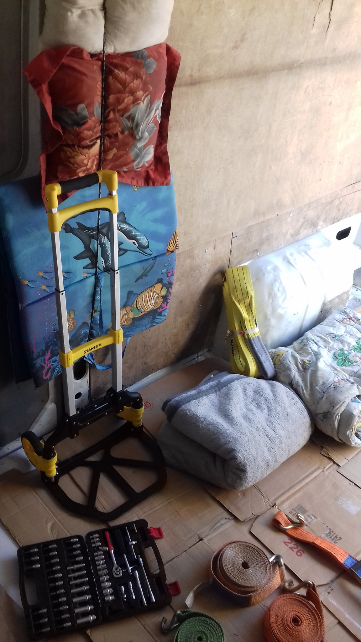 Wózek transportowy Stanley z rozłożoną podstawą, narzędzia, pasy transportowe i zabezpieczone koce w przestrzeni ładunkowej