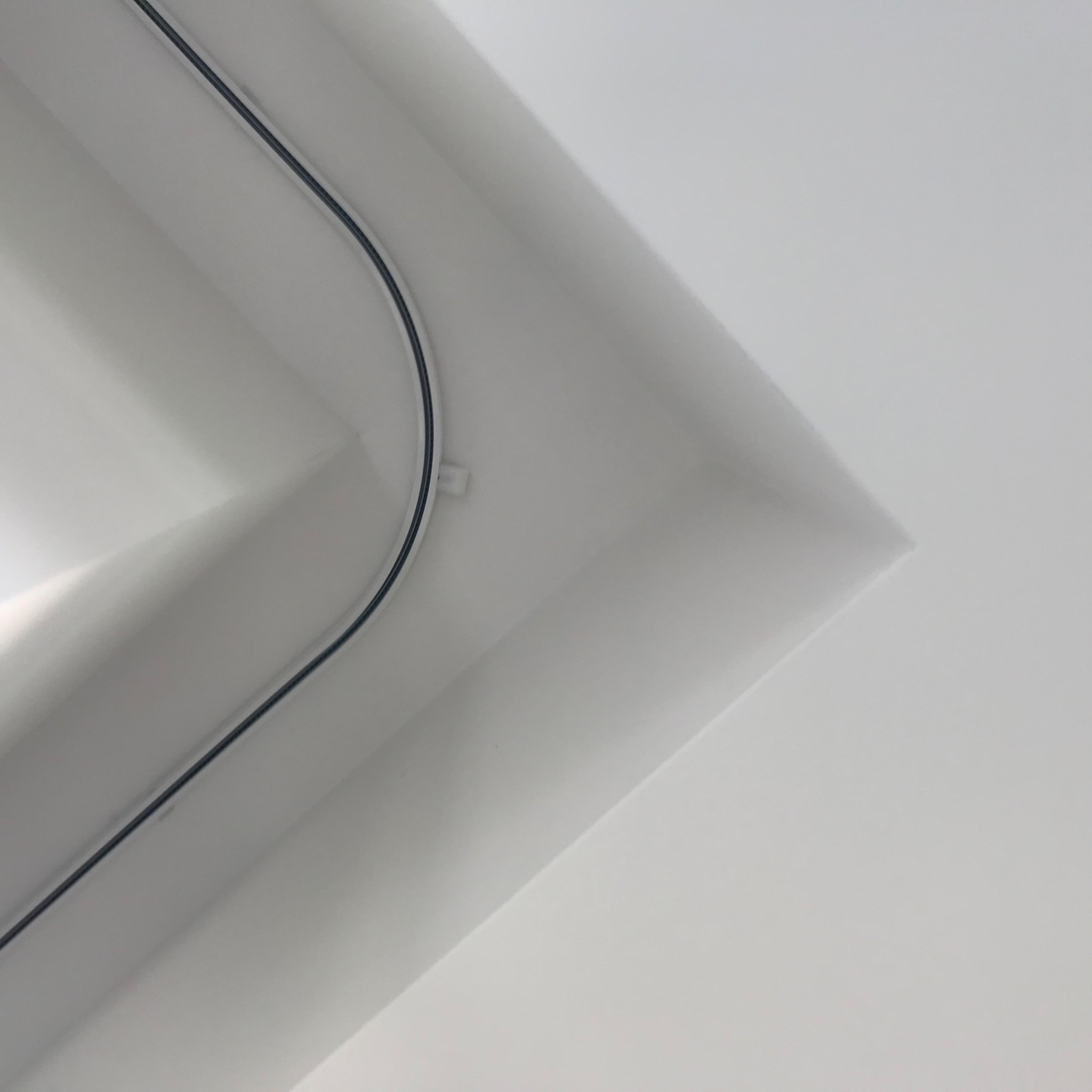 Minimalistyczne ujęcie białego sufitu z widoczną szyną karnisza w rogu pomieszczenia.