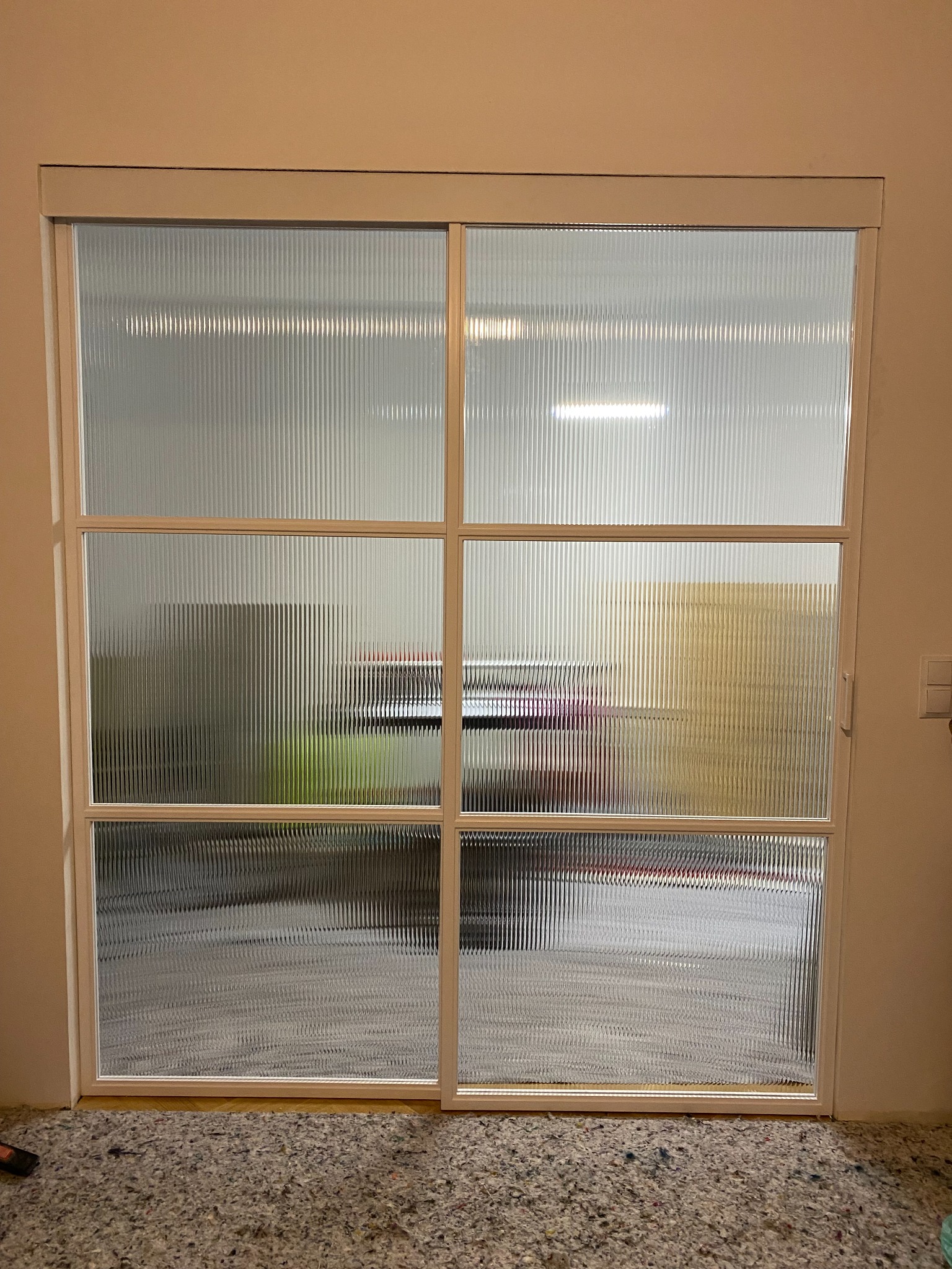 Segment drzwi przesuwnych z białymi profilami i szybą hartowaną typu flutes, widoczne obustronne domykanie firmy GEZE.