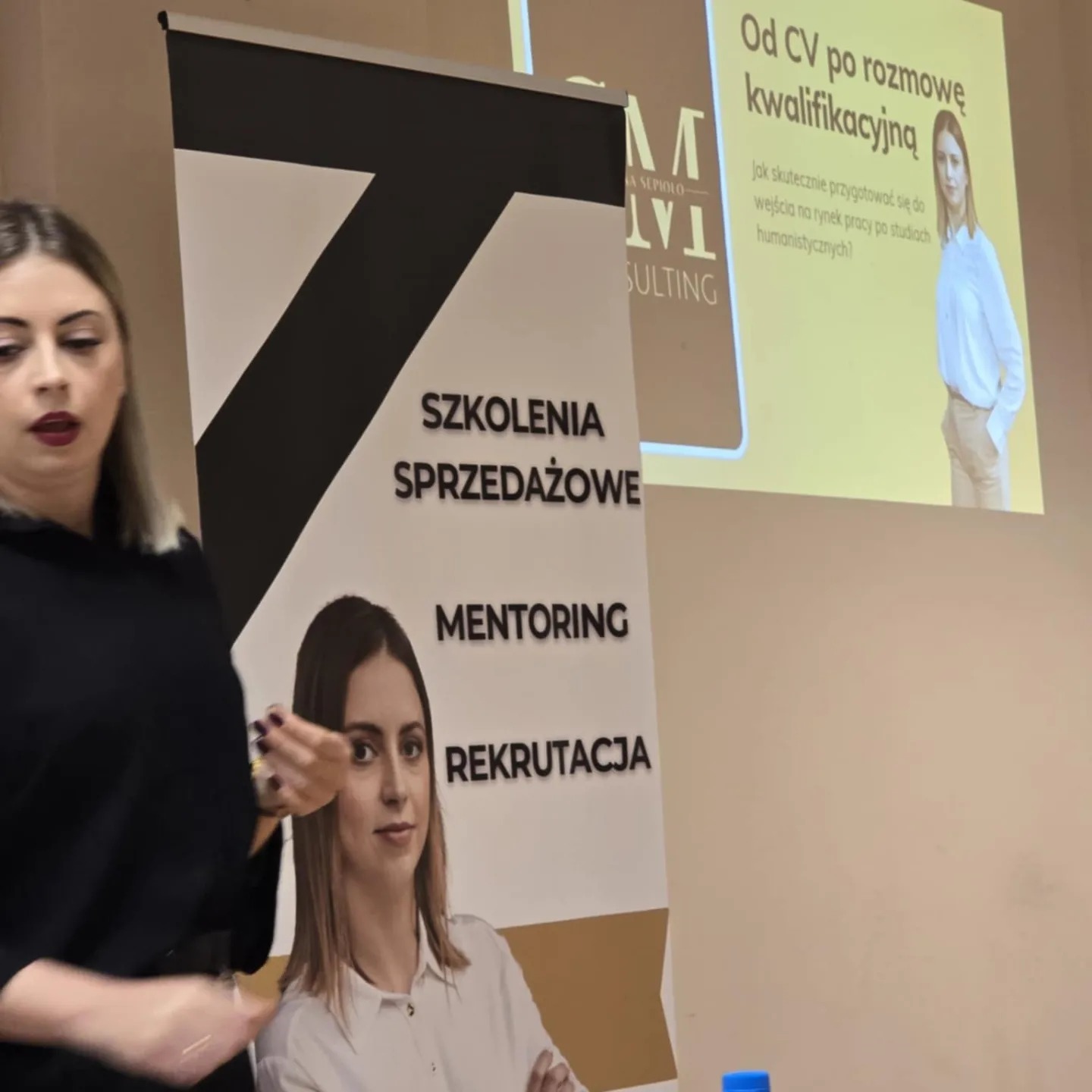 Prezentacja z zakresu szkoleń sprzedażowych i rekrutacji, z widocznym banerem firmy i slajdem o przygotowaniu do rozmowy kwalifikacyjnej. Osoba prowadząca szkolenie w kadrze.