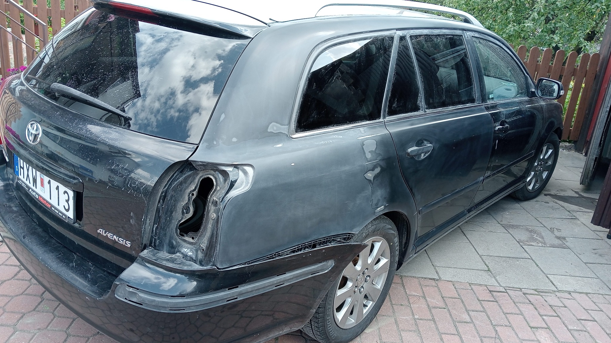 Przygotowanie do lakierowania tylnej części czarnego kombi Toyota Avensis z widocznymi śladami szlifowania i brakiem lampy.