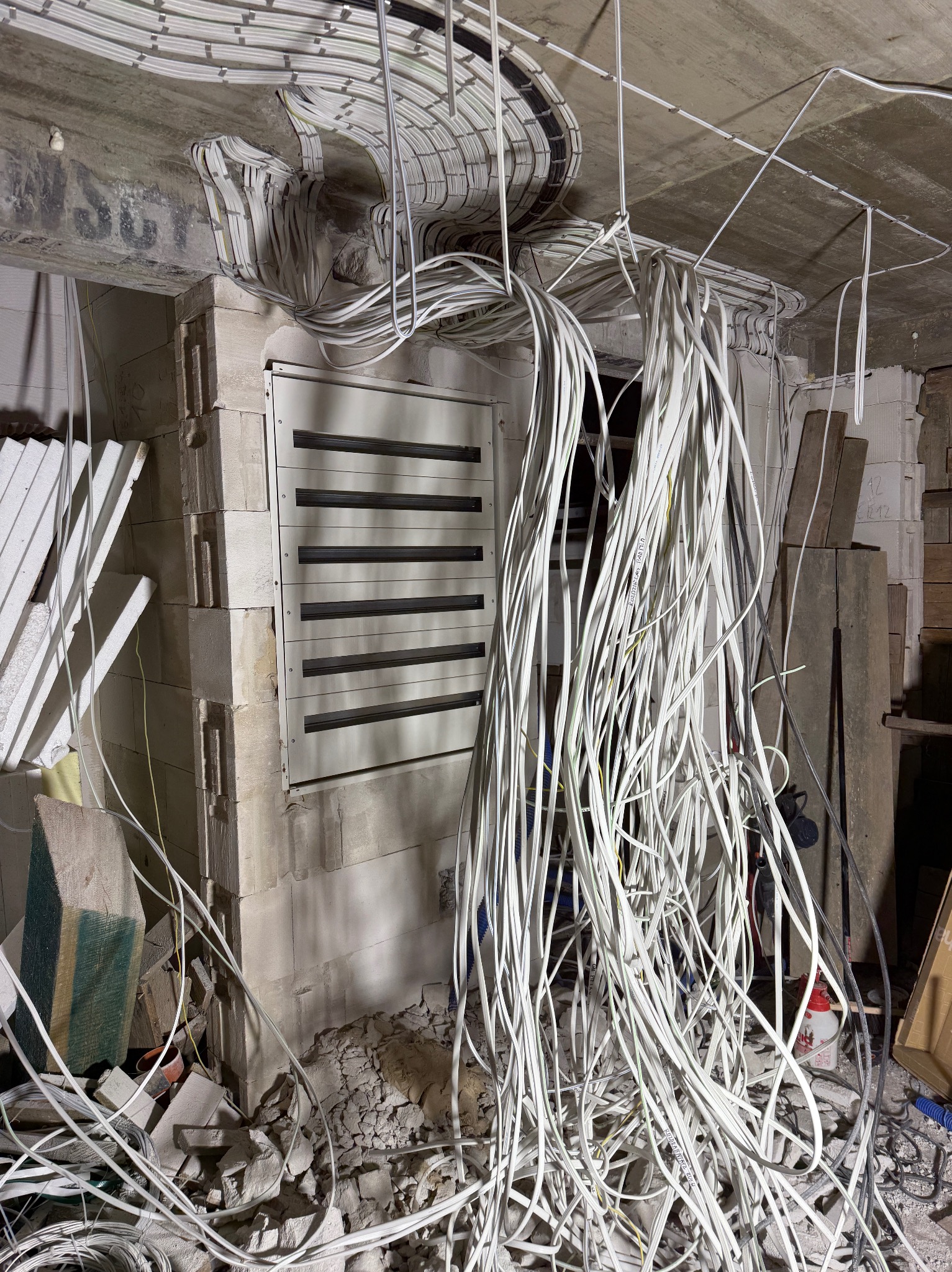 Rozłożone kable elektryczne w surowym wnętrzu, widoczne puszki instalacyjne i fragmenty ścian z betonu komórkowego. Etap prac instalacyjnych przed wykończeniem.