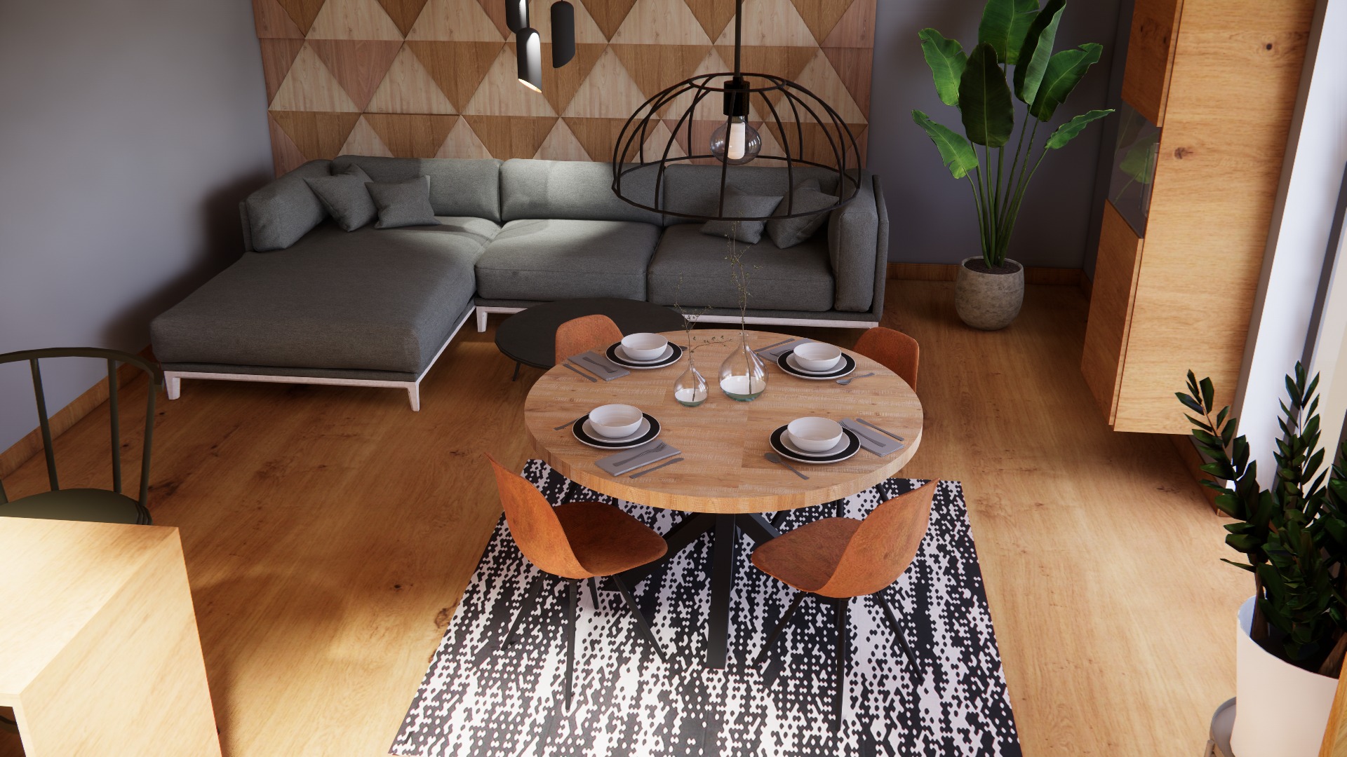 Wnętrze salonu z jadalnią: szary narożnik, okrągły drewniany stół z nakryciem dla pięciu osób, pomarańczowe krzesła, wzorzysty dywan, drewniana ściana i szafka, oświetlenie punktowe i wisząca lampa...