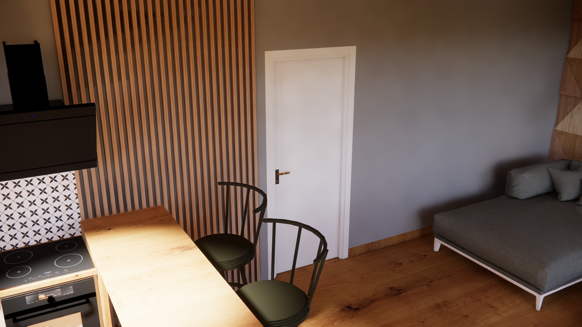 Wnętrze kawalerki z aneksem kuchennym, drewnianym blatem, czarną płytą indukcyjną, okapem, dwoma krzesłami barowymi i szarą sofą.