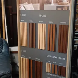 Ekspozycja paneli lamelowych Linerio firmy Vox, prezentująca różne warianty kolorystyczne i profile: S-Line, M-Line, L-Line oraz listwy wykończeniowe w odcieniach Natural, Mocca i Chocolate.
