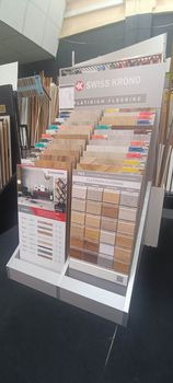 Ekspozycja próbek paneli podłogowych marki Swiss Krono, prezentująca różnorodność wzorów i kolorów, umieszczona na białym stojaku w sklepie.