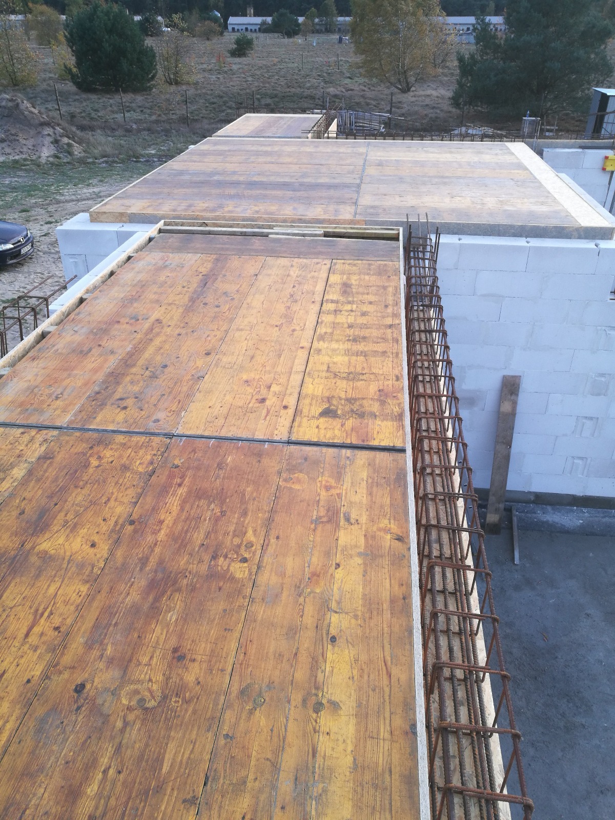 Wylany strop z drewnianym szalunkiem i zbrojeniem na ścianach z betonu komórkowego, widok z góry na budowę domu jednorodzinnego.