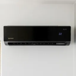 Czarny klimatyzator Rotenso z wyświetlaczem temperatury 22 stopnie, zamontowany na białej ścianie, obok okna z żaluzjami.