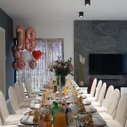 Tango sala bankietowa & catering - Uroczysty stół na osiemnastkę: biały obrus, złote dekoracje, balony, kwiaty i napoje. Przygotowany do świętowania w nowoczesnym wnętrzu.