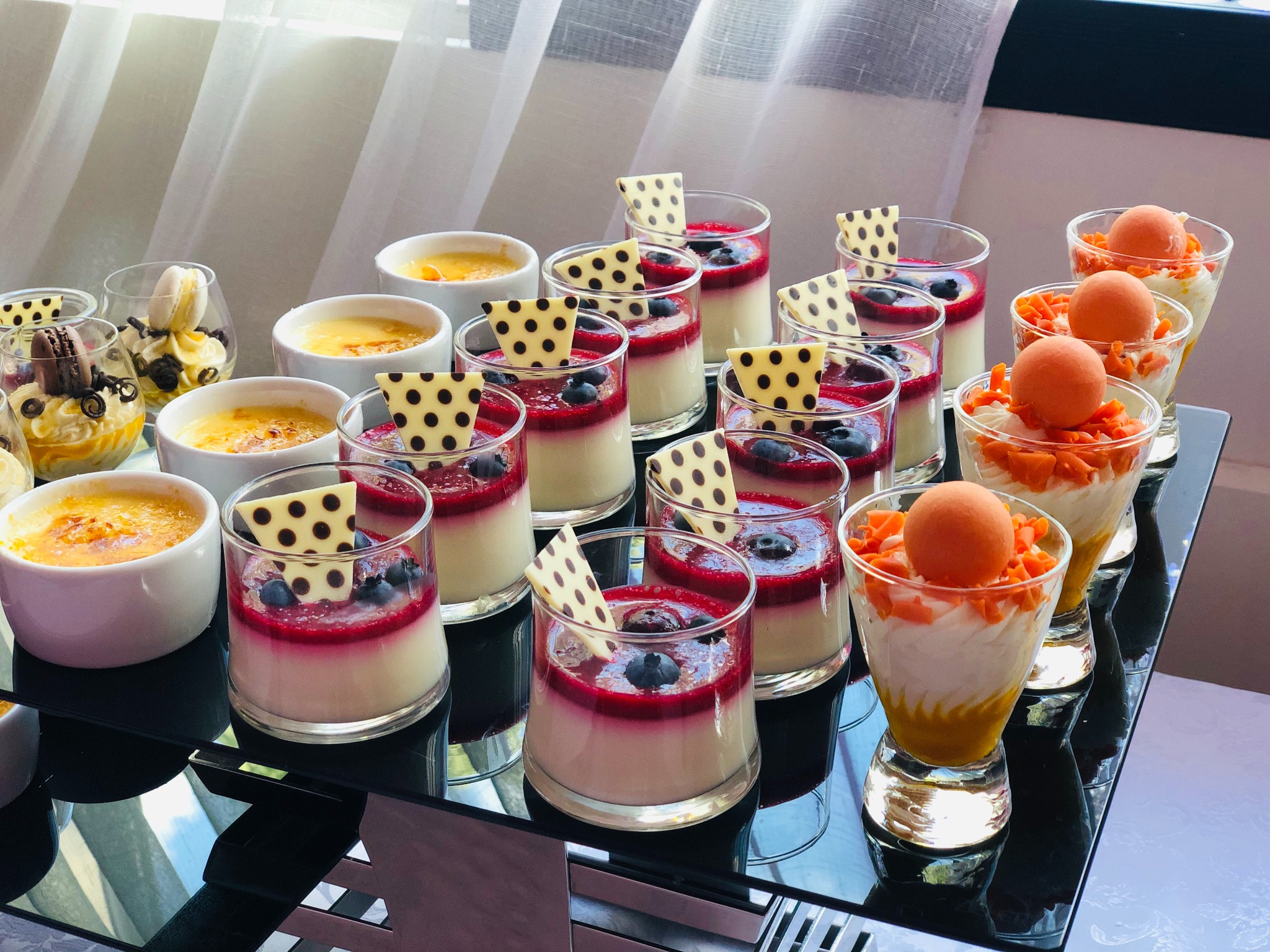 Elegancki bufet deserowy: krem brûlée, panna cotta z owocami i czekoladą, mus z mango. Idealne na catering firmowy i świąteczny.