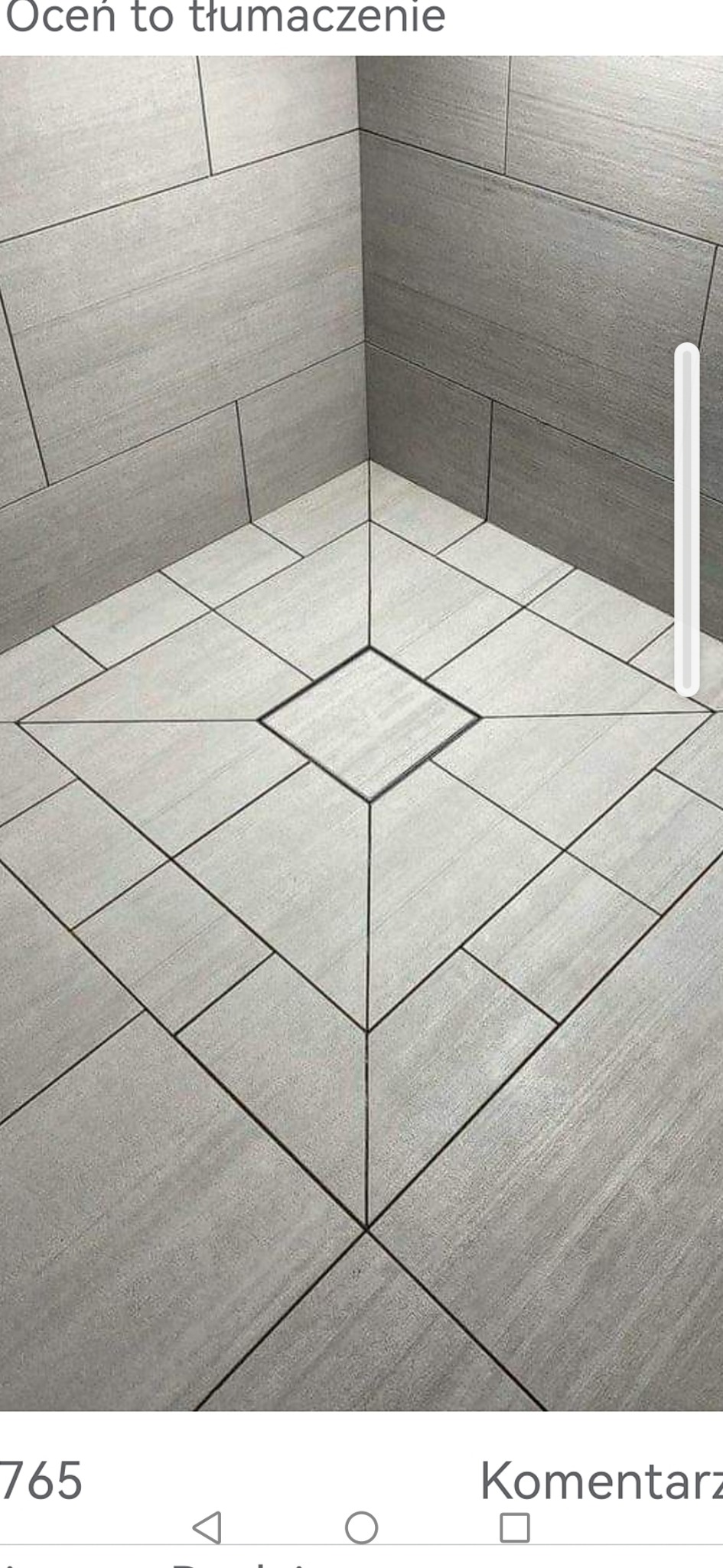 Szare płytki ceramiczne ułożone w geometryczny wzór na podłodze i ścianach kabiny prysznicowej z odpływem liniowym w kształcie kwadratu.