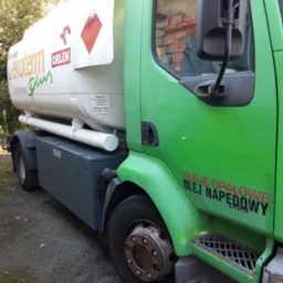 Ciężarówka cysterna w kolorze zielonym z białym zbiornikiem, z logo Orlen i napisem 'Ekotherm Plus', oraz informacją o przewozie cieczy łatwopalnych. Na kabinie widoczny napis informujący...