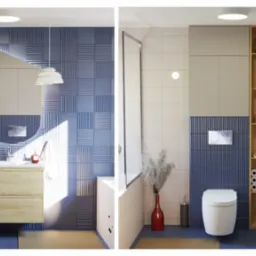 Nowoczesna łazienka z niebieskimi płytkami 3D, drewnianą szafką pod umywalką i lustrem o nieregularnym kształcie, obok toaleta i szafka z zapasem papieru toaletowego oraz logo firmy Kliminowska...