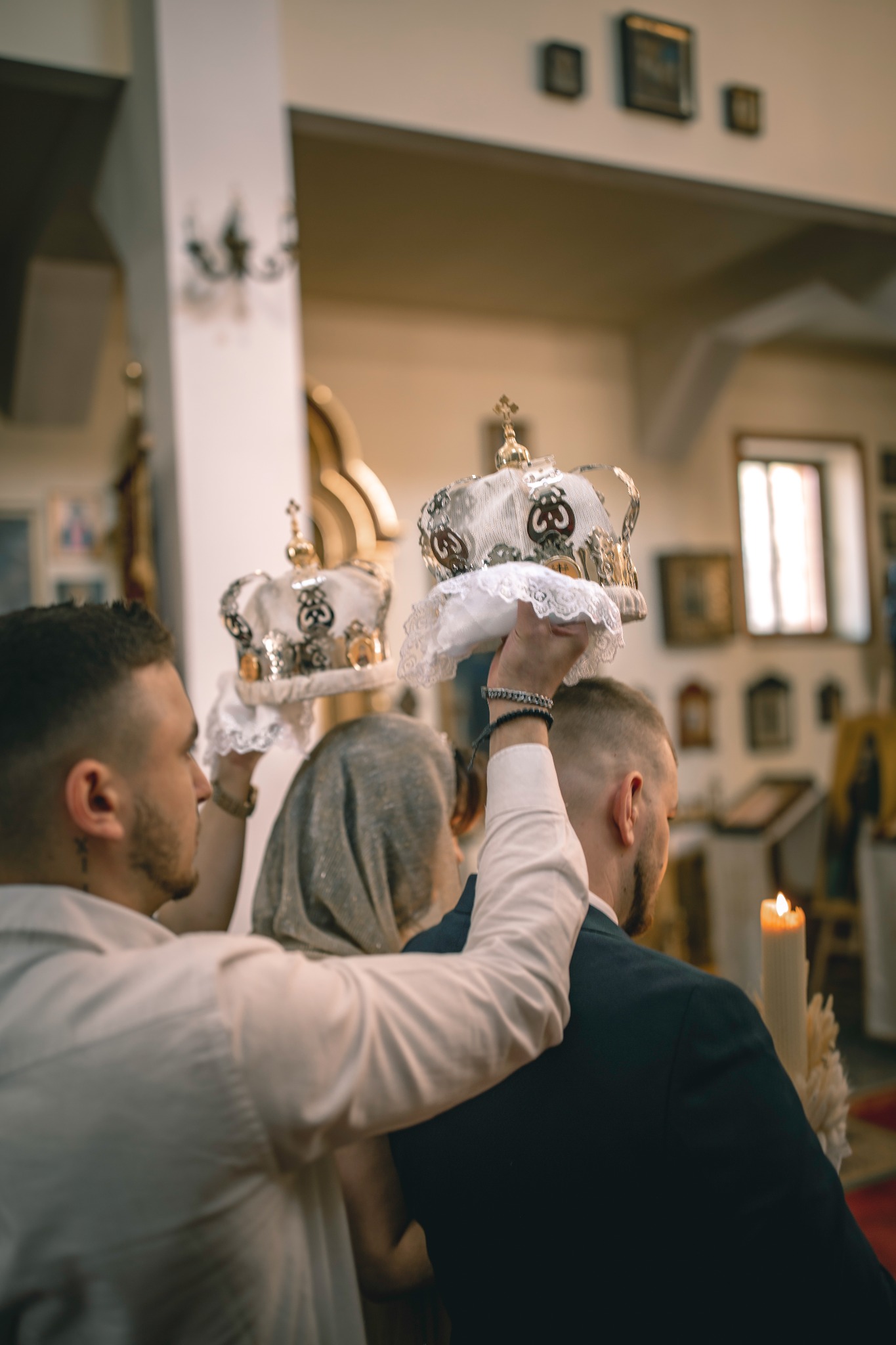 Uroczystość zaślubin w kościele w Poznaniu: asystenci trzymają korony nad głowami młodej pary podczas ceremonii.