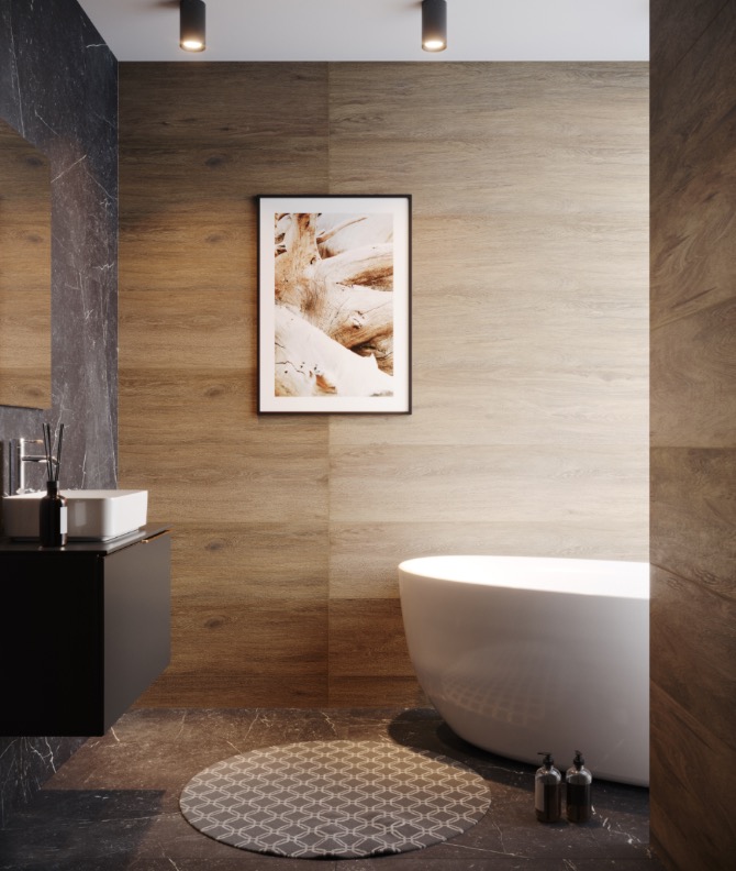 Minimalistyczna łazienka z drewnopodobnymi płytkami, wolnostojącą białą wanną, czarną szafką z umywalką i okrągłym dywanikiem na marmurowej podłodze; na ścianie wisi grafika w czarnej ramie.