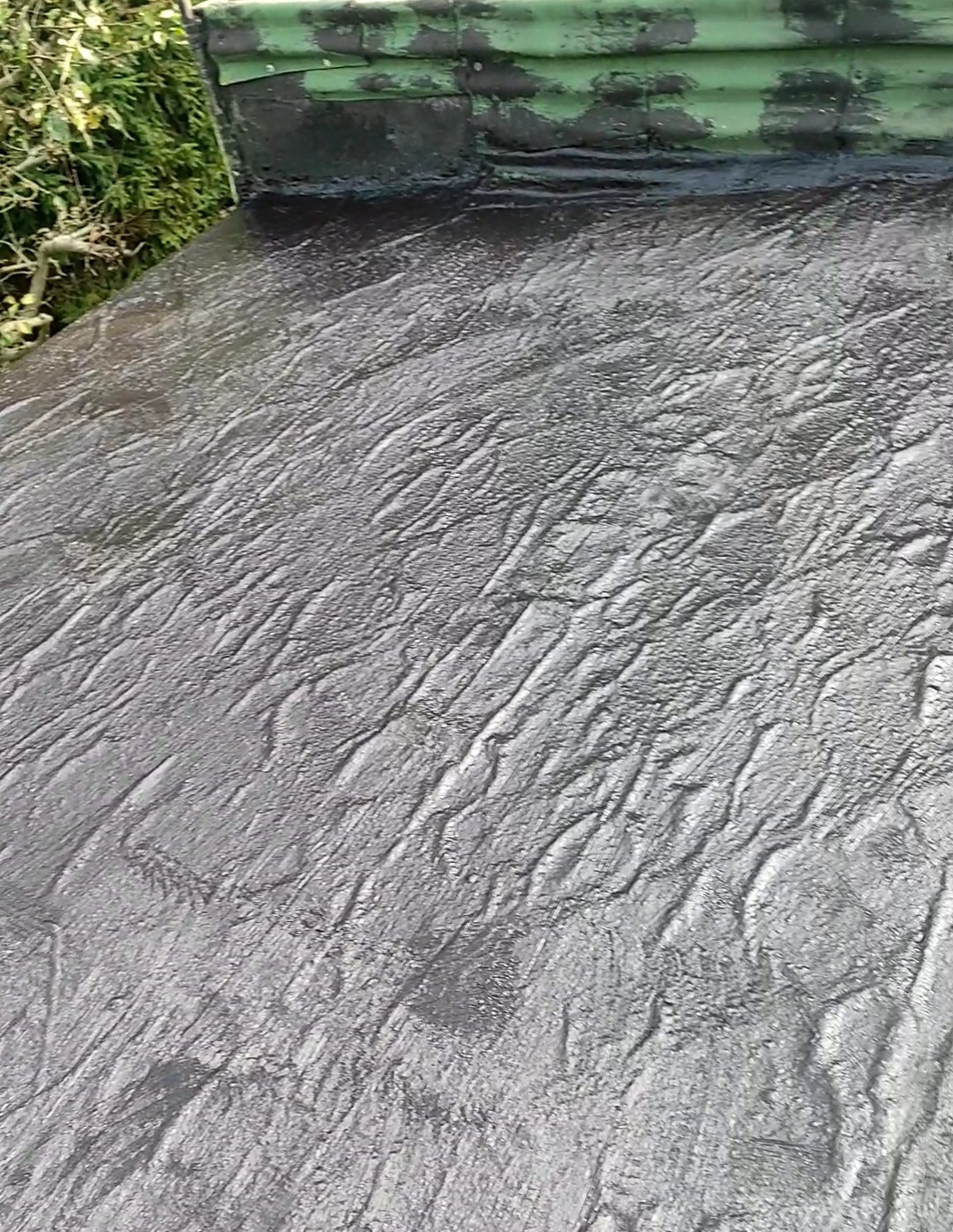 Szara, nierówna powierzchnia ziemi po wykopie, z widocznymi śladami narzędzi i resztkami roślinności w tle.