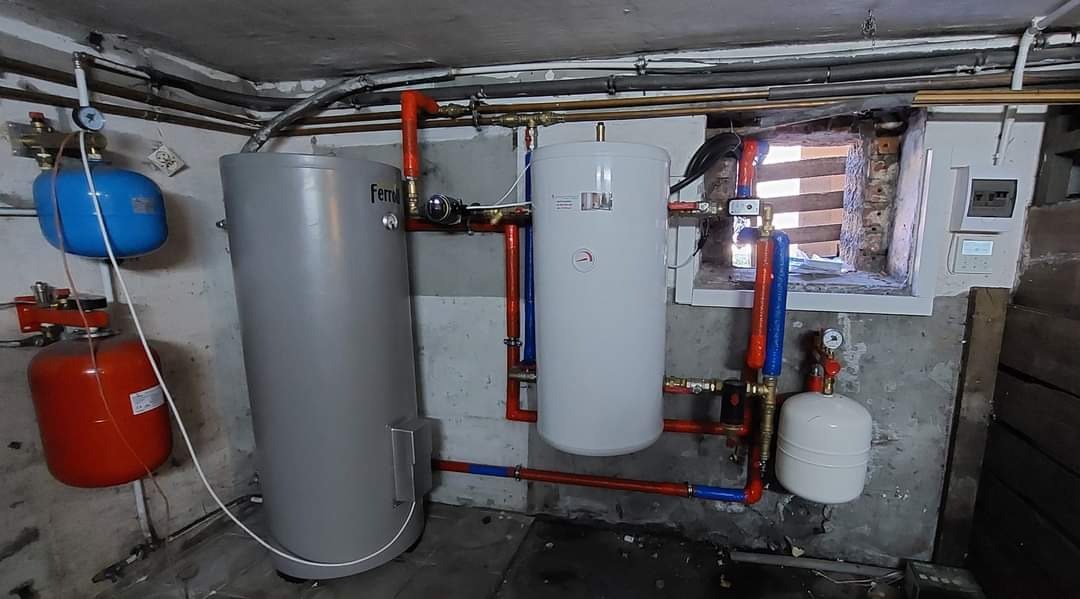 Szara i biała instalacja zbiorników z rurami w piwnicy z małym oknem i brudnymi ścianami.