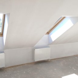 RAFFENER Rafał Jasiukajć - Poddasze ze świeżo pomalowanymi na biało ścianami, trzema oknami dachowymi i grzejnikami, podłoga przygotowana pod dalsze prace wykończeniowe.