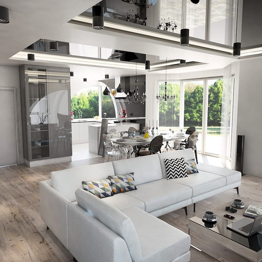 Przestronne, nowoczesne wnętrze salonu z kuchnią w tle, biała sofa narożna z geometrycznymi poduszkami, przeszklony sufit z czarnymi lampami, parkiet w naturalnym odcieniu drewna.