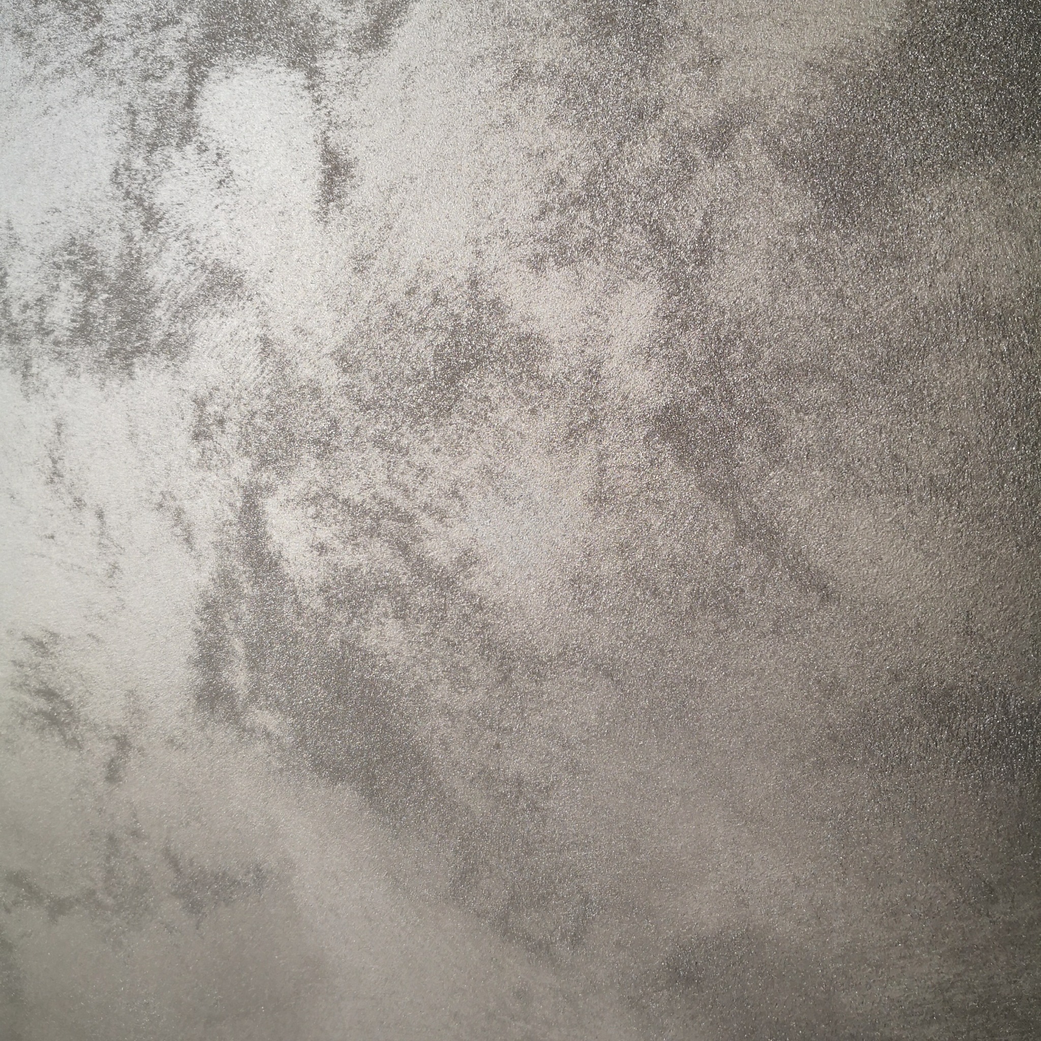 Srebrzysta, dekoracyjna faktura na ścianie z efektem cieniowania i delikatnym połyskiem.